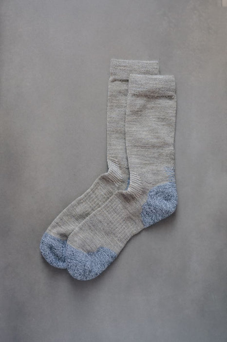 Pair of beige socks with blue toe post and heel on a grey background
