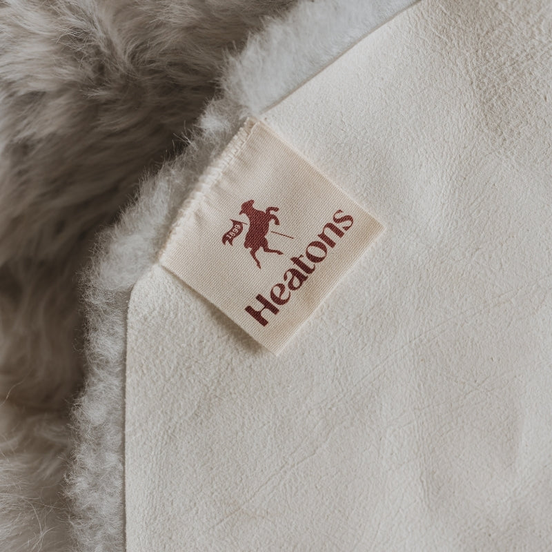 Close-up of a 'Heatons' label on a textured fabric surface.
