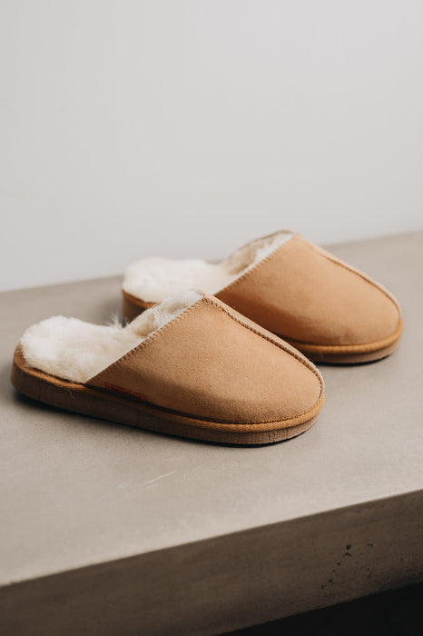 A pair of tan men's mule slippers with a light sheepskin.