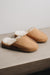 A pair of tan men's mule slippers with a light sheepskin.