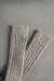 Ribbed beige natural merino wool sock on a light grey background - detail of ribbed sock neck