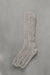 Ribbed beige natural merino wool sock on a light grey background.