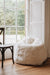 White sheepskin bean bag chair in a room with large windows.