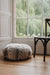 Melange sheepskin ottoman on a wooden floor with a large window in the background