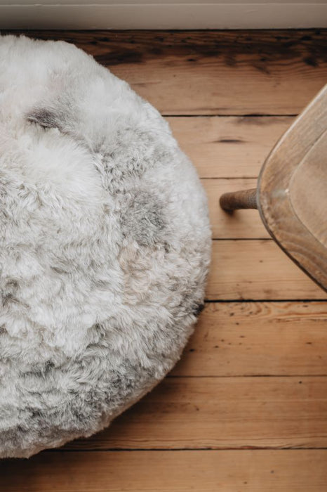 Round sheepskin ottoman on a wooden floor