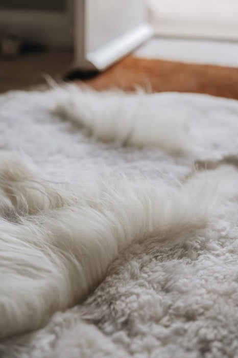 Close-up of a white designer rug of mixed lengths and tones with a blurred background
