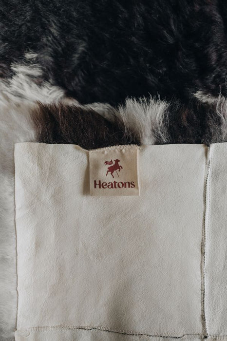Close-up of a sheepskin rug with a 'Heatons' label.