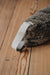 Brown sheepskin draught excluder with light handle on a wooden floor