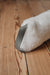 White sheepskin draught excluder with brown / grey leather hang tab on a wooden floor