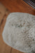 Close-up of the bottom of an oatmeal sheepskin door stop with a zipper on a wooden surface
