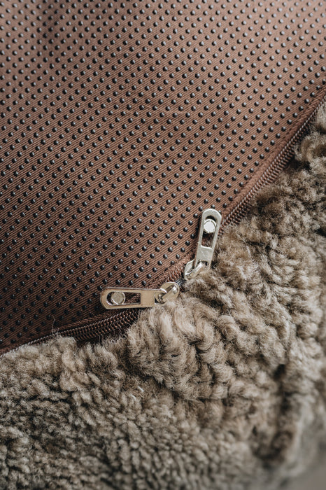 Close-up of a zipper on a brown fabric surface that is the bottom of a sheepskin beanbag.