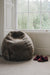 Wheat brown sheepskin bean bag chair next to a window with a pair of slippers on a carpeted floor.