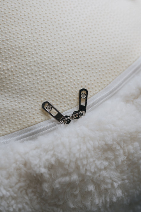 Close-up of a zipper on a textured white surface that is the bottom of a sheepskin beanbag.