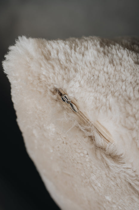 Close-up of an oatmeal sheepskin floor cushion showing a zipped entry point.