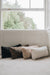 Four sheepskin cushions in black, brown, beige, and white on a light-coloured carpet with a window in the background.