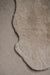 Close-up of an oatmeal sheepskin rug on a similar coloured carpet