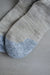 Close up view of Beige merino wool socks with blue toe post grey background