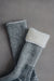Pair of grey and black merino socks with cuff turned over showing white looped wool inner on a grey background