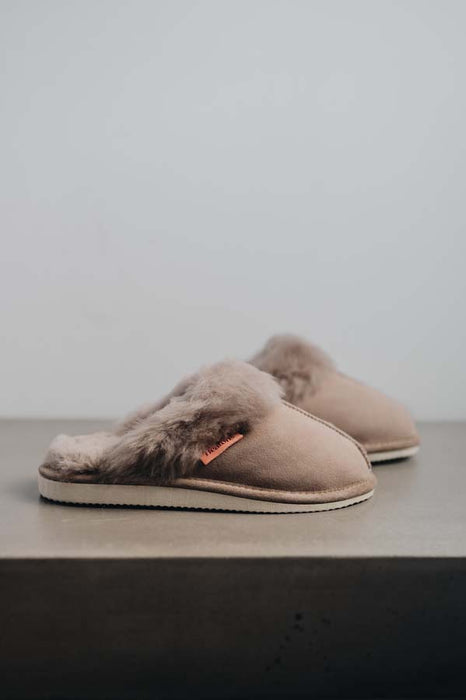 Gwen Stone Sheepskin Slippers with Heatons label detail on Concrete Surface