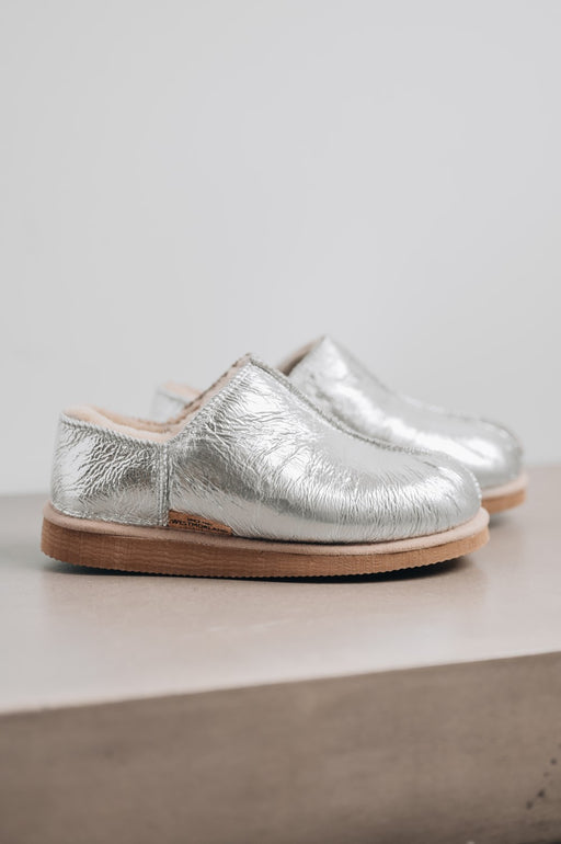 Side View of Cadi Silver Sheepskin Slippers on Concrete Surface