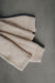 Folded beige wool legwarmers on a gray background