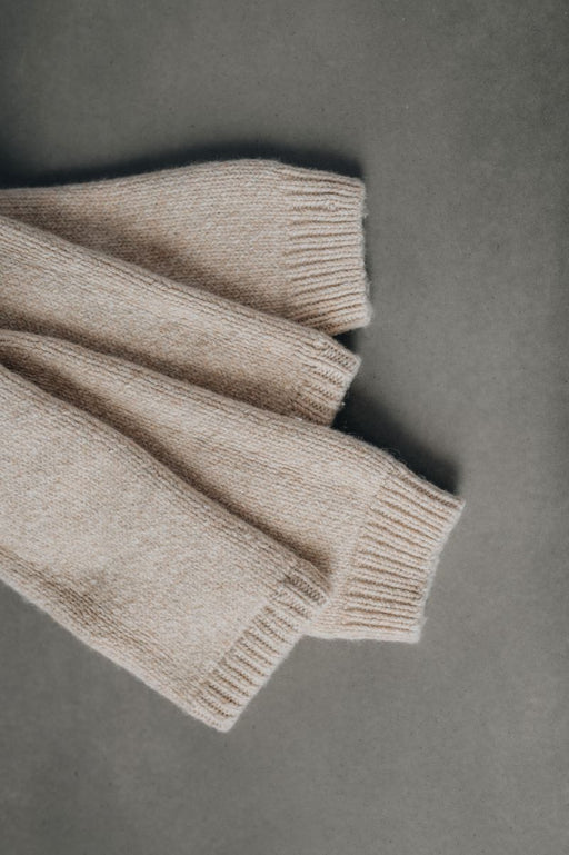 Folded beige wool legwarmers on a gray background