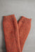 Pair of rust knitted woolen leg warmers on a gray background
