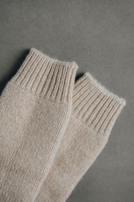 Pair of beige knitted socks on a gray background
