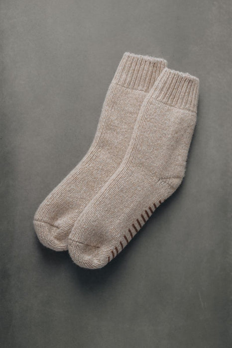 Pair of beige wool grip socks or bed socks on a gray background