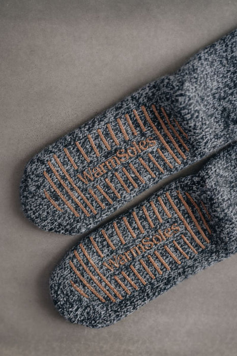 Pair of blue slipper socks with brown sole pattern on a gray back ground - WarmSoles 
