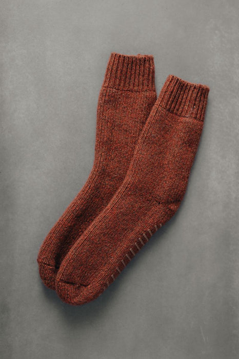 Pair of brown knitted wool bed socks on a gray background