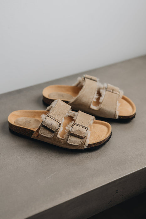 High angle of the vanilla mead slippers with metal buckles and a vanilla sheep skin with sheep wool on the inside