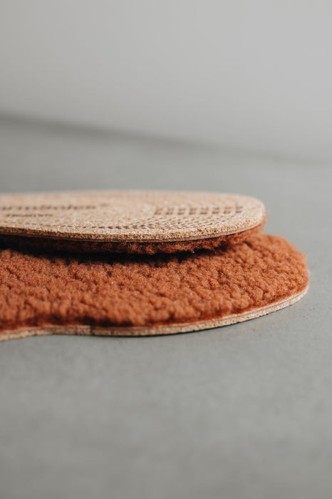 Two  brown isheepskin nsoles on a gray background