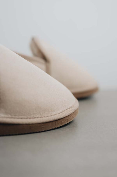 Close up of vanilla sheepskin slippers on a stone surface