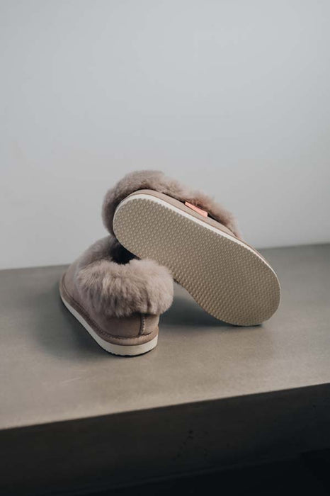 Ruby Stone Sheepskin Slippers showing the bottom of the EVA sole on a Concrete Surface