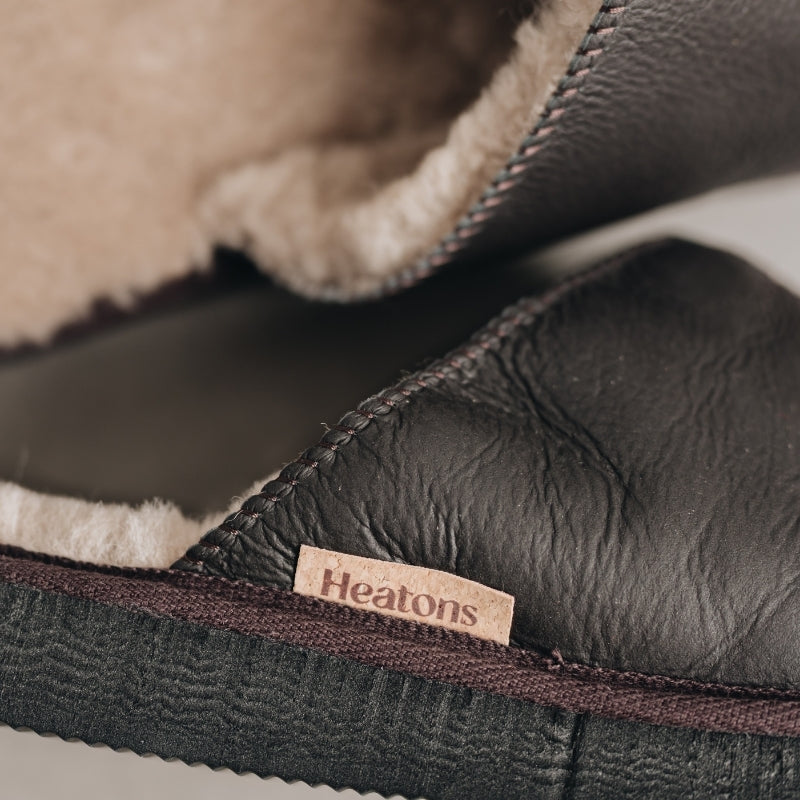 Close-up of a dark brown slipper with a 'Heatons' label, showing texture and stitching details.