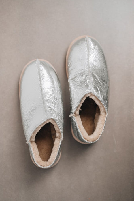 Birds Eye View of Cadi Silver Sheepskin Slippers on Concrete Surface