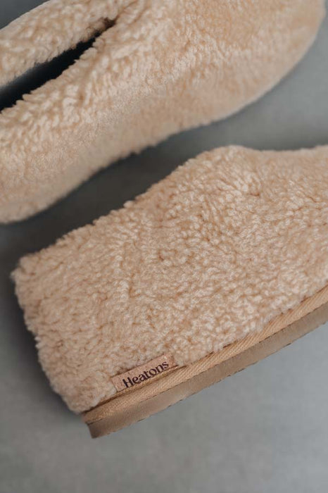 Side view of a camel coloured curly merino sheepskin boot slipper with natural cork Heatons brand label