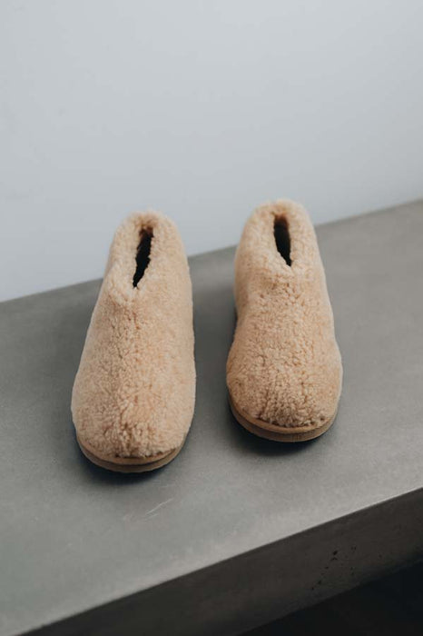 Front view of a camel coloured curly merino sheepskin boot slipper.