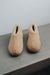 Front view of a camel coloured curly merino sheepskin boot slipper.