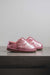 Side View of Cadi Metallic Pink Sheepskin Slippers on Concrete Surface