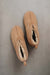 A pair of tan slip-on sheepskin slippers with white shearling lining, photographed from a top-down angle on a textured grey background. Slipper is named Erin.