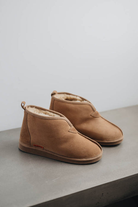 Profile view of Noah Tabac Sheepskin Slippers on Concrete Surface