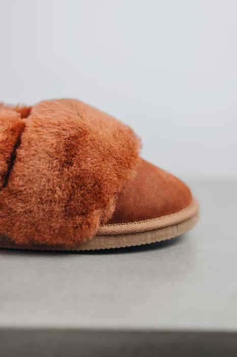 Close up of the toe of a rust coloured sheepskin slipper detailing the suede and wool collar