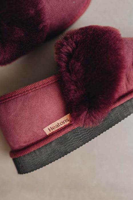 Close-up of a pair of Heatons slippers featuring deep burgundy full sheepskin cuff, suede outer and a dark grey textured sole