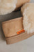 Close-up of a tan suede slipper with fluffy cream shearling lining and an orange 'Heatons' brand tag.