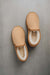 Birds eye view of a pair of tan sheepskin slippers with white wool lining on a stone bench