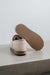 Vanilla sheepskin slipper with brown PVA sole on a light concrete surface