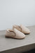 Pair of vanilla sheepskin slippers on a concrete surface 