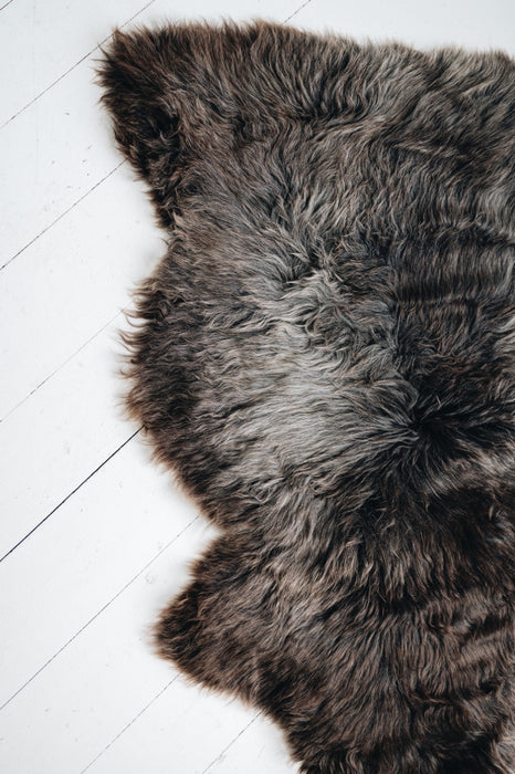 Soft Natural Brown British Sheepskin Rug contrasting against a hard and stark white wooden floor.
